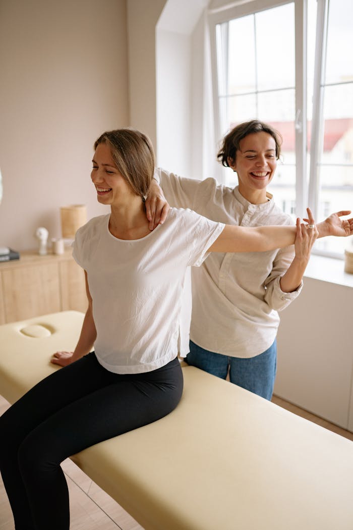 Mastering the First Impression: Your intriguing post title goes here A therapist guides a woman in a stretching exercise on a massage table in a clinic setting.