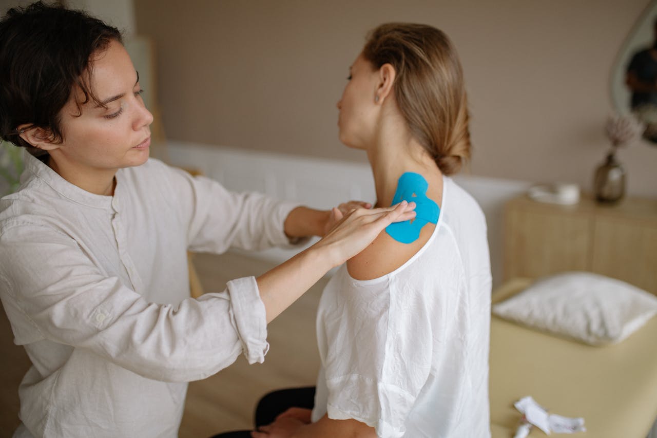 Crafting Captivating Headlines: Your awesome post title goes here A physiotherapist applies blue kinesiology tape to a patient's shoulder for muscle support.